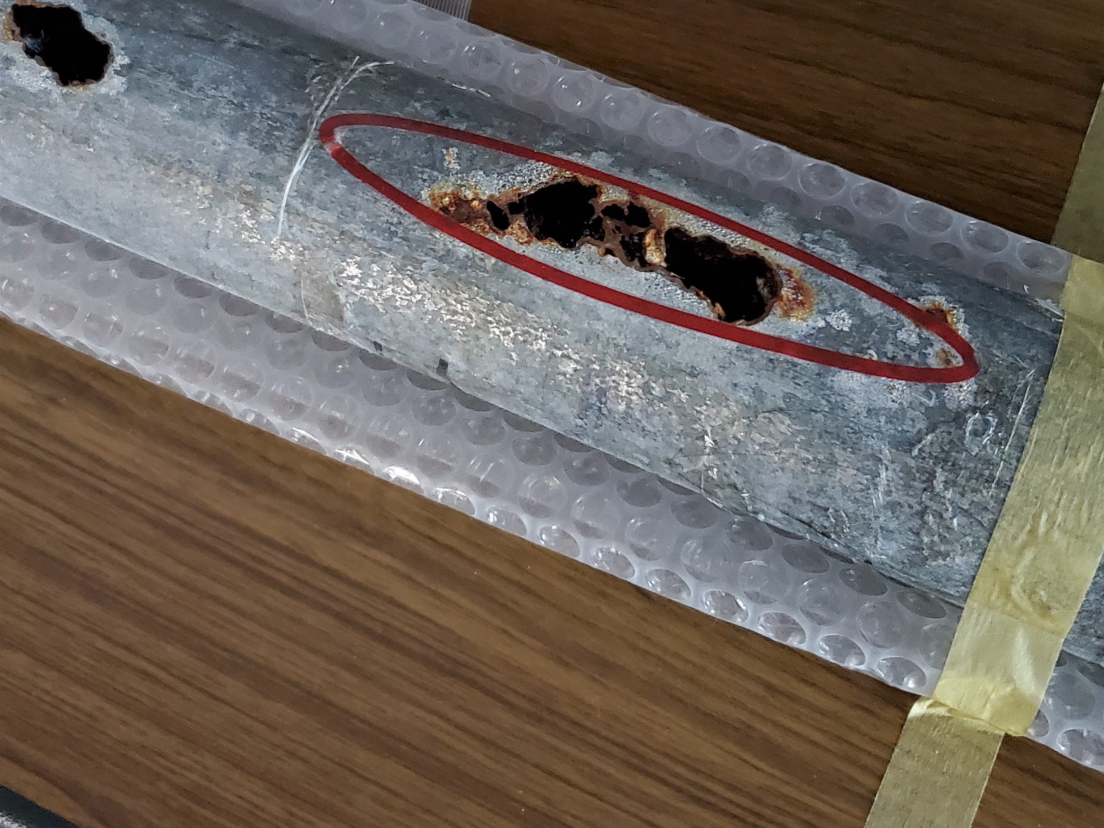 腐食が進み、管の側面に穴が開いた排水管。